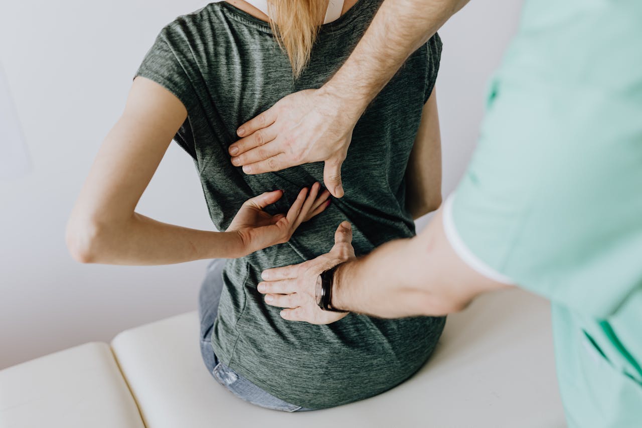 Physiotherapist assessing a patient's lower back in a clinic
