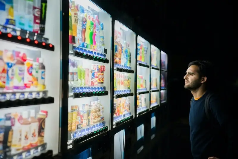 man looking at drinks in vending machine