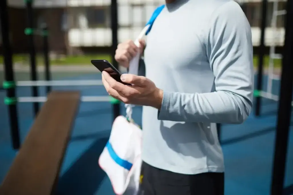 athlete reviewing cpa in digital marketing metrics on a sports app on his smartphone after training.
