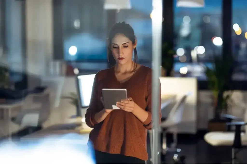 Businesswoman using tablet to review 'what is a digital marketing strategy' components after hours.