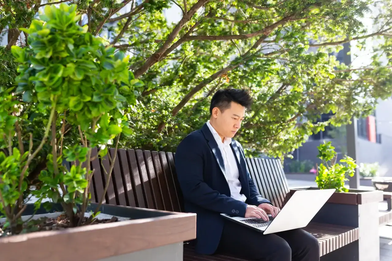 singapore digital marketing consultant focused on a laptop while working outdoors in an urban setting.